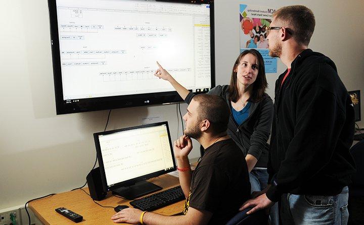 Three computer science major students work together as a group.